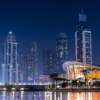 Stunning view of Dubai's illuminated skyline with modern skyscrapers reflecting on water at night.