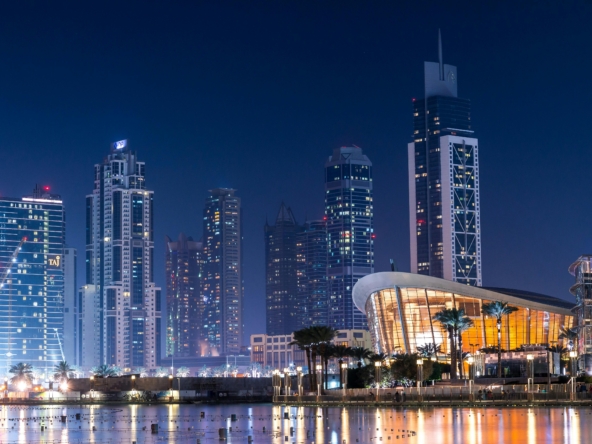 Stunning view of Dubai's illuminated skyline with modern skyscrapers reflecting on water at night.